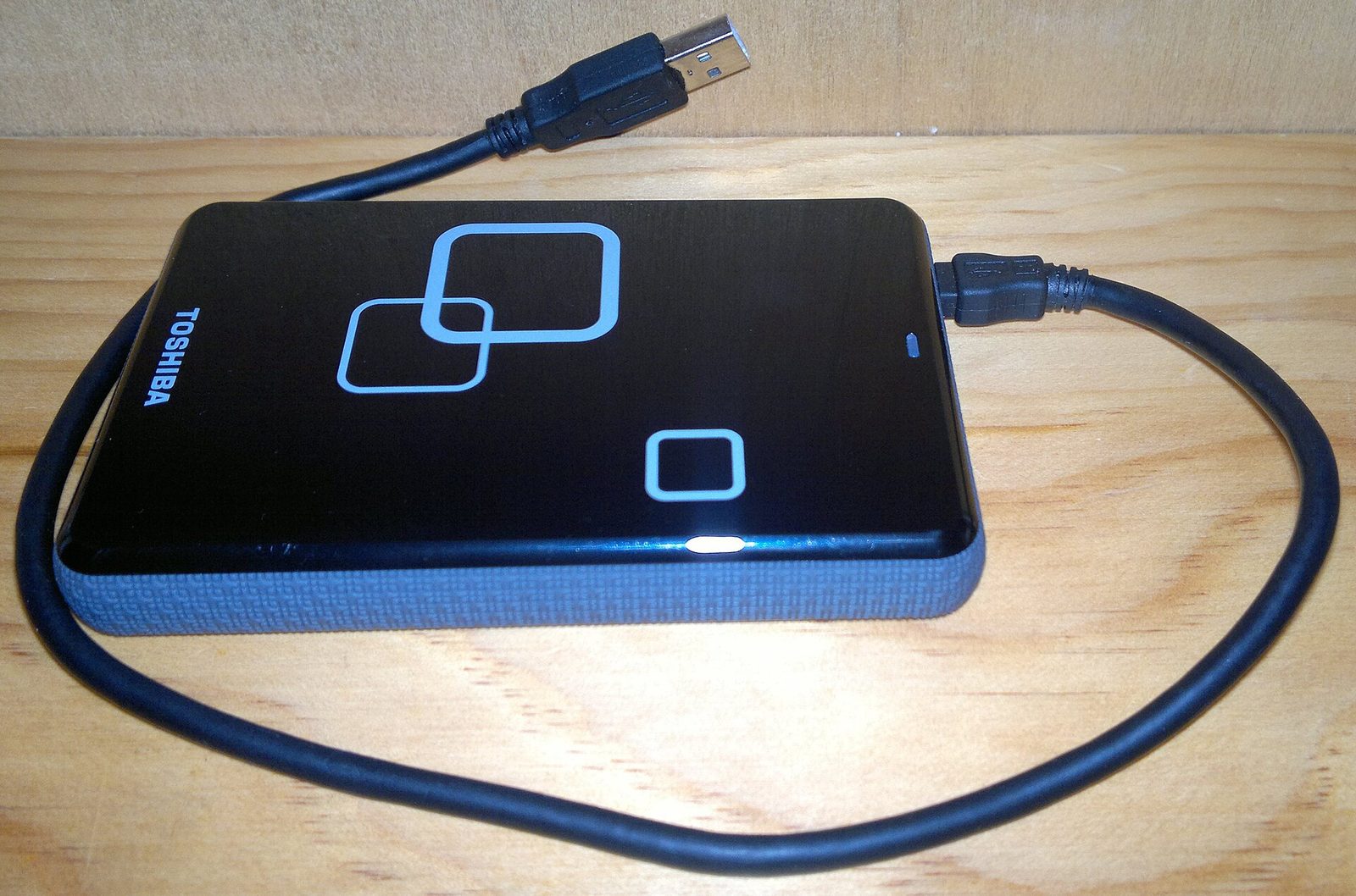 Un disque dur externe posé sur une table, câble USB branché
